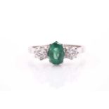 A platinum, diamond, and emerald ring, set with an oval-cut emerald of approximately 1.0 carats,