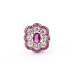 A platinum, diamond, and ruby ring, the stylised mount centred with a mixed oval-cut ruby within a