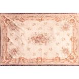 A 20th century ivory ground Aubusson style tapestry carpet with a central spray of roses within a