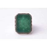 An Eastern white metal gentleman's ring set with a canted rectangular green hardstone panel intaglio
