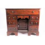 A George III mahogany kneehole dressing chest, the frieze drawer with adjustable writing surface and