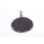 A Safavid carved dark green jade pendant in silver metal mount, of oval form, engraved with