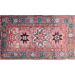 An old red ground Kazak rug with three-star for lozenges on a field of geometric device. Within