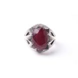 An Eastern white metal gentleman's ring set with oval cut red stone, mounted with pierced triangular