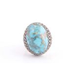 A large Persian silver gentleman's ring, set with a turquoise coloured stone, a short inscription on