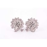 A pair of stylised flowerhead earclips, mid 20th century, each centred by seven round brilliant