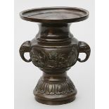 Vase. Bronze mit brauner Patina. Gedrückt kugelige Wandung auf hohem, reliefierten Fu