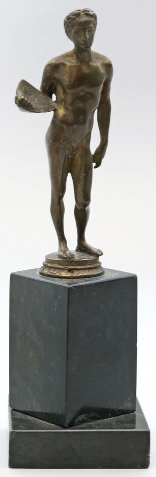 Skulptur eines Männeraktes mit Schild und Lorbeerkranz. Bronze mit beriebener Patina.
