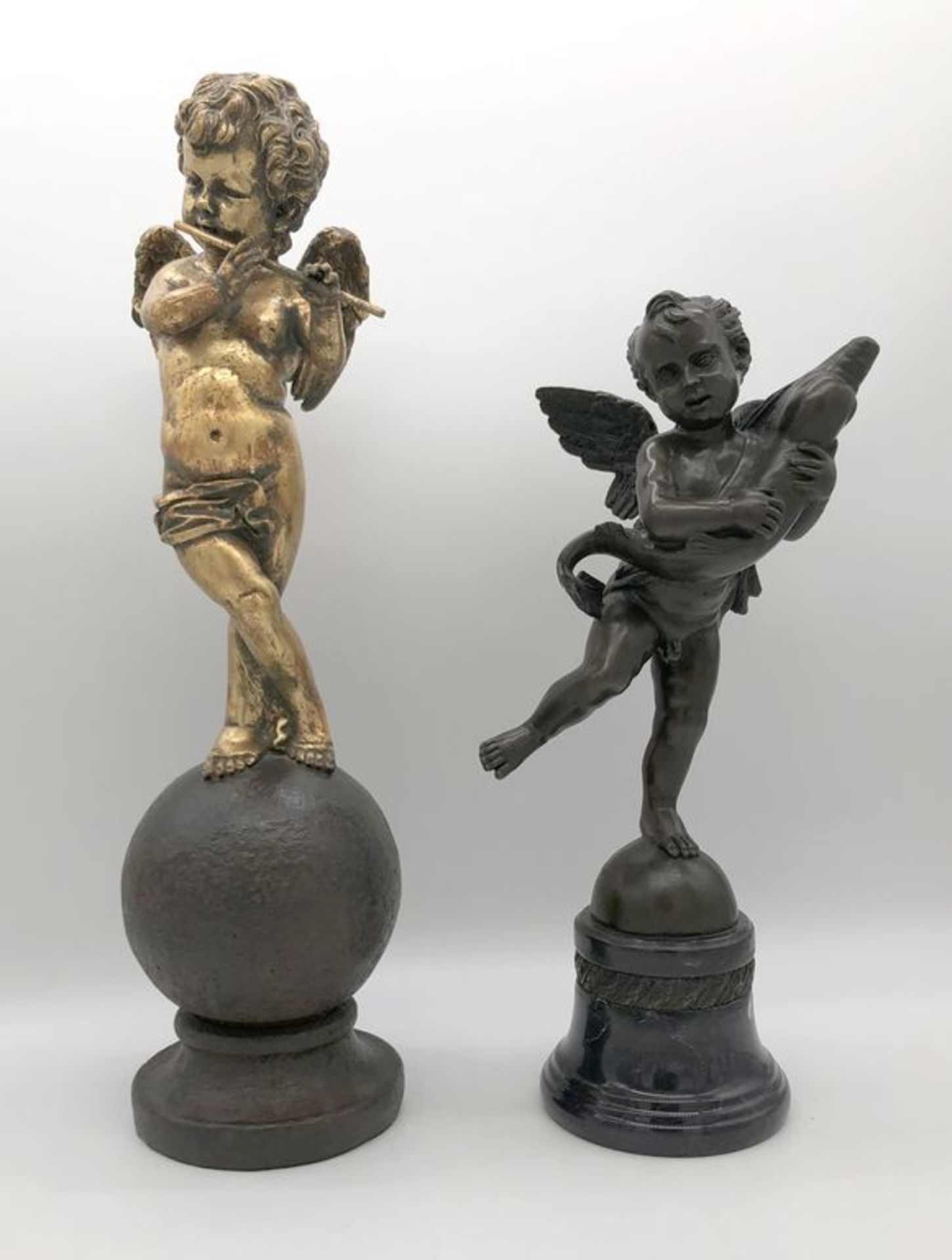 Zwei Skulpturen "Putto mit Delphin und Flöte". Braun patinierte Bronze, auf Marmorsockel bzw.