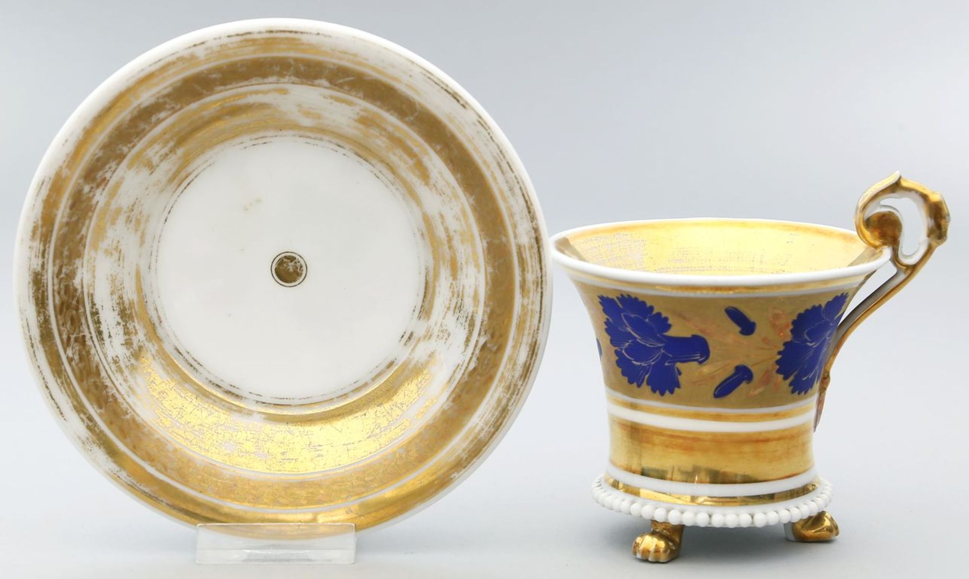 Tasse und Untertasse. Porzellan. Tasse mit blauer Kornblumenmalerei über Goldfond und reicher