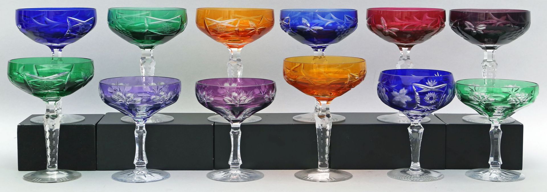 12 Sektschalen. Farbloses Glas mit farbigem Überfang und Facettschliffen. 20. Jh. H. 12 bis 15 cm.