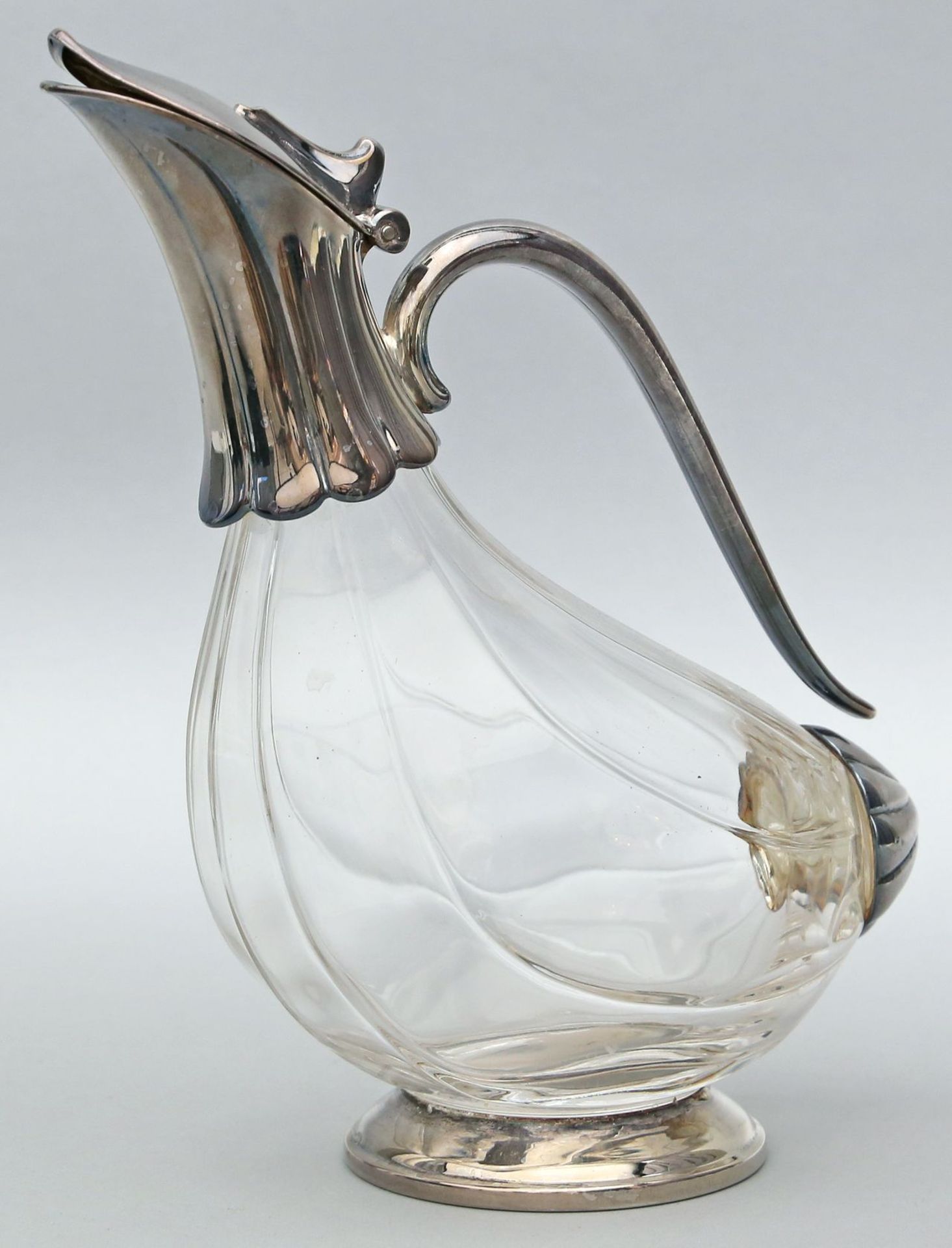 Karaffe in stilisierter Entenform. Farbloses Glas mit versilberter Metallmontage. 20. Jh. H. 25 cm.