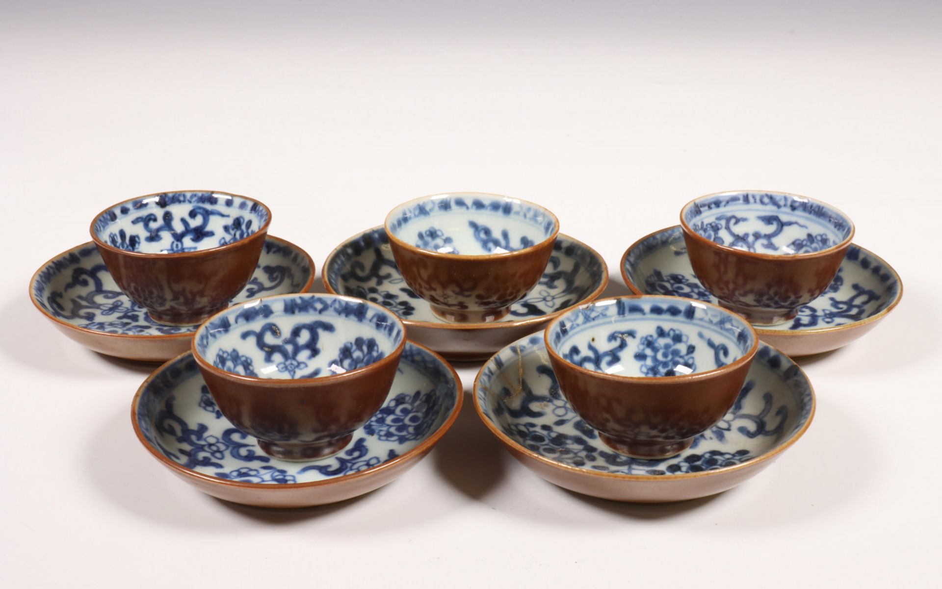 China, een set van vijf blauw-wit en café-au-lait geglazuurde koppen en schotels, 18e eeuw,