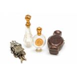 Twee kristallen parfumflacons en een zilveren miniatuurklokje.