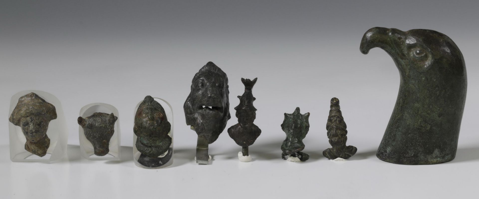 Roman bronze head of a falcon, and a collection of nine Roman bronze human- and animal heads, ca. 1s