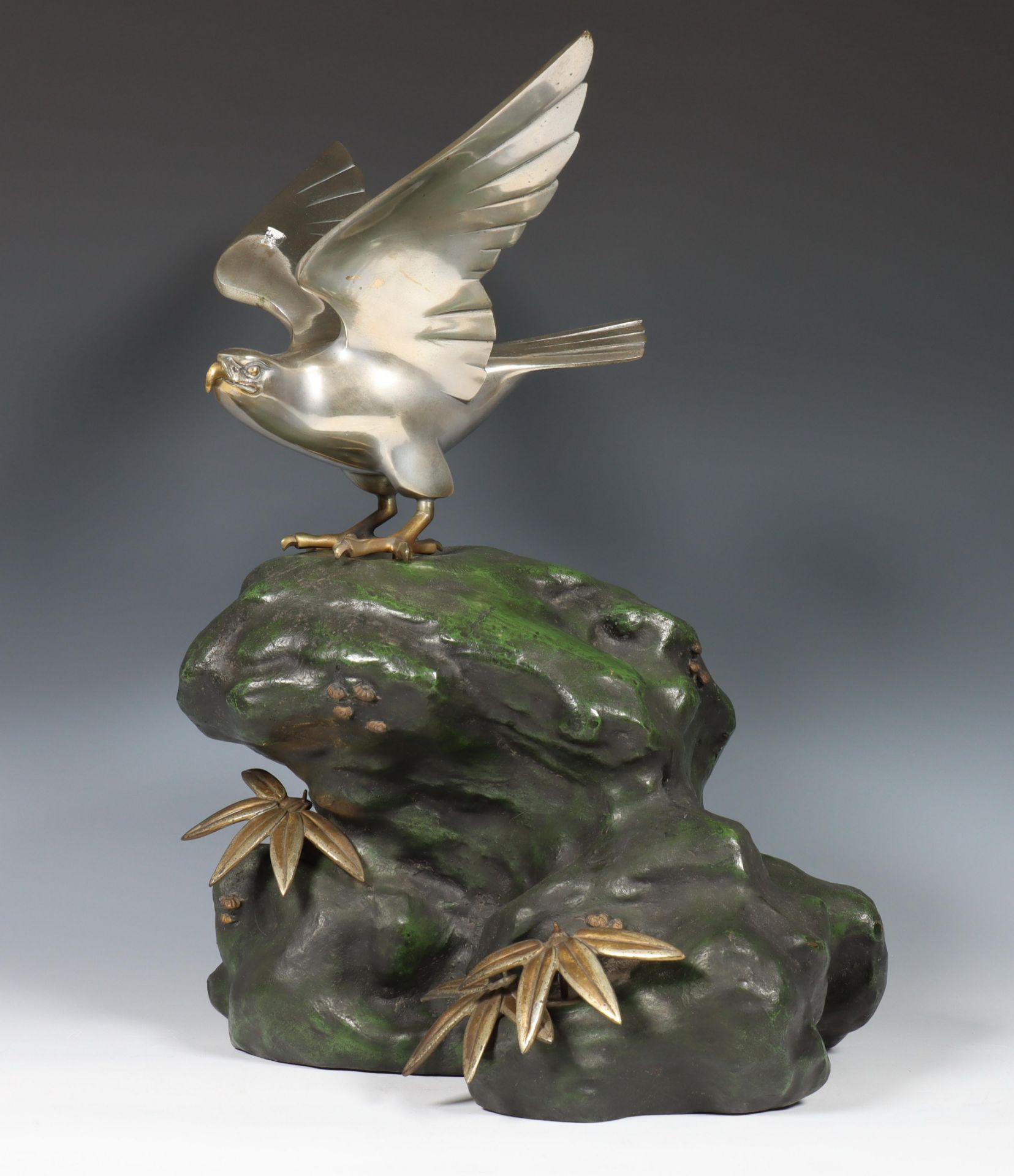 Japan, metal okimono of a silver-coloured hawk on green-patinated rockwork, signed to hawk