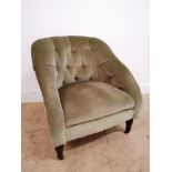 An Edwardian button backed tub chair upholstered in green fabric and raised on turned supports and