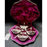 Cased set of four Victorian silver salts and spoons in the dimpled style of handled baskets with