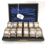 Fine cased set of twelve silver napkin rings decorated with floral chasing and miniature gadroon