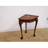 A reproduction corner table having a moulded top raised on tapering legs and ball and claw feet.
