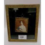 A gilt metal frame with easel containing a portrait miniature of a lady.