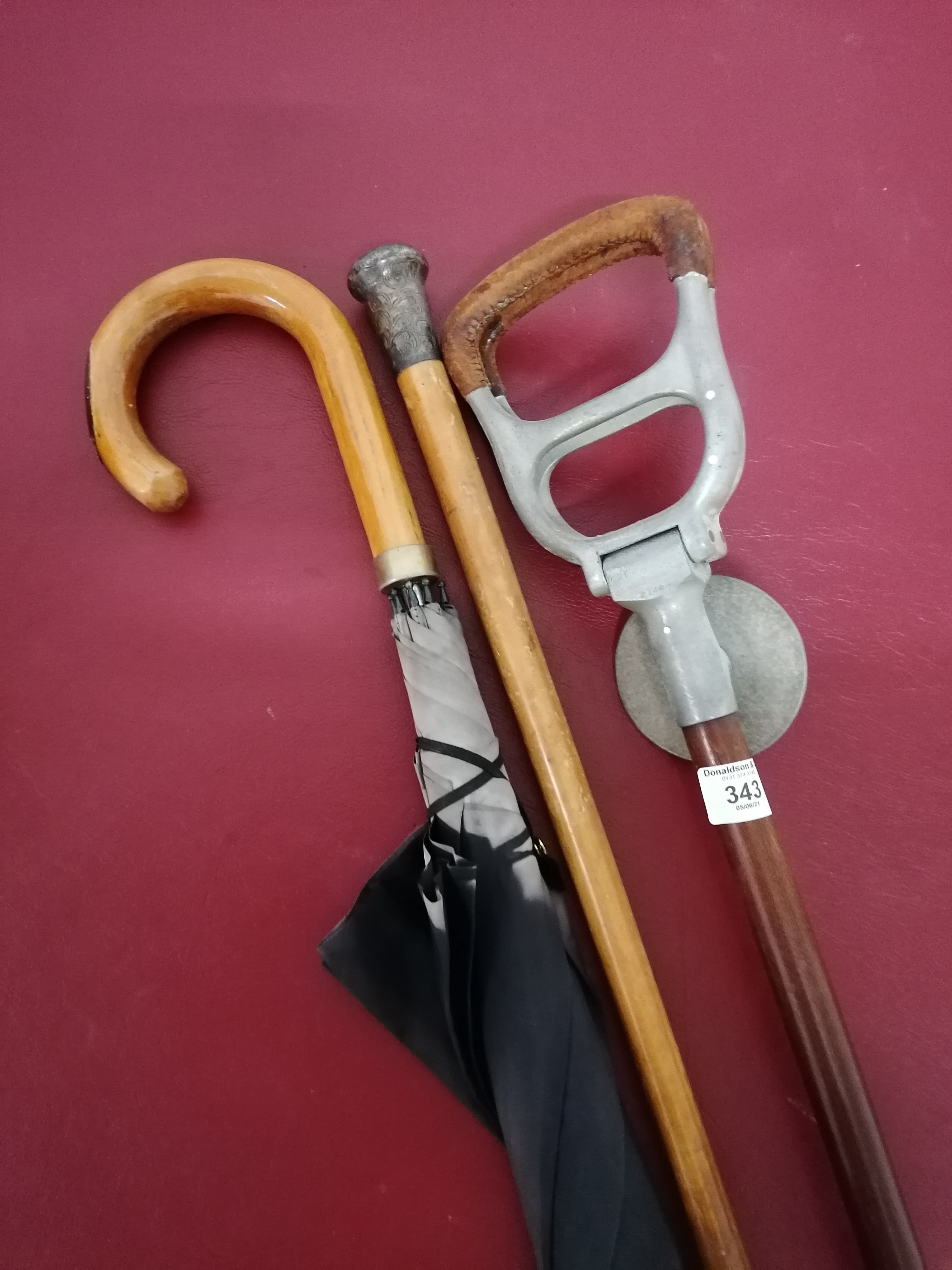 A 19th century silver topped walking cane together with a shooting and umbrella.