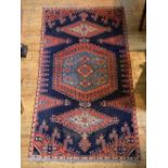 IRANIAN HAMADAN CARPET  with central red and blue motif on a pale blue ground with a narrow biege