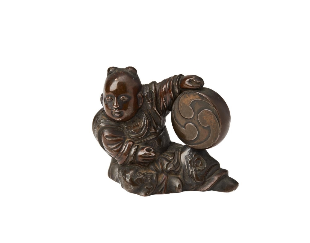 BRONZE SCROLL WEIGHT QING DYNASTY, 19TH CENTURY modelled as a seated boy holding a drum 5cm high  PR