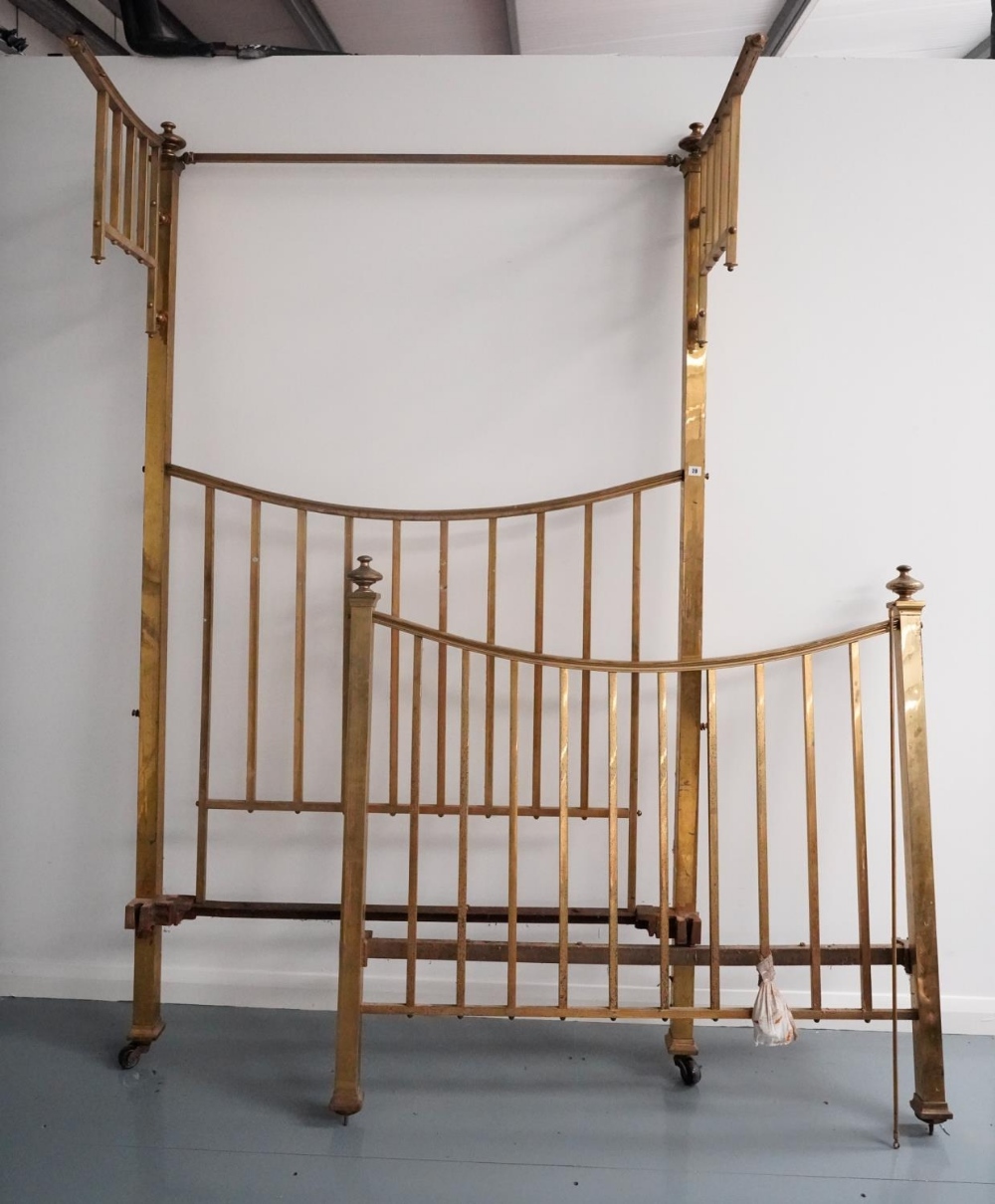 AN EDWARDIAN BRASS TESTER BED, the square section frame with curved end rails, the head with two