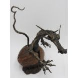 A CONTEMPORARY CAST METAL FIGURE OF BABY DRAGON EMERGING FROM EGG, the egg made from a coconut shell