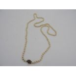 A STRING OF PEARLS WITH A 9CT GOLD SEED PEARL AND GARNET SET CLASP 46cm LONG