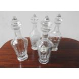 FOUR CUT GLASS DECANTERS WITH STOPPERS, one with a ceramic decanter label, 33cm high