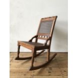 A VICTORIAN MAHOGANY CANE SEATED ROCKING CHAIR, with cane panel back and turned spindle