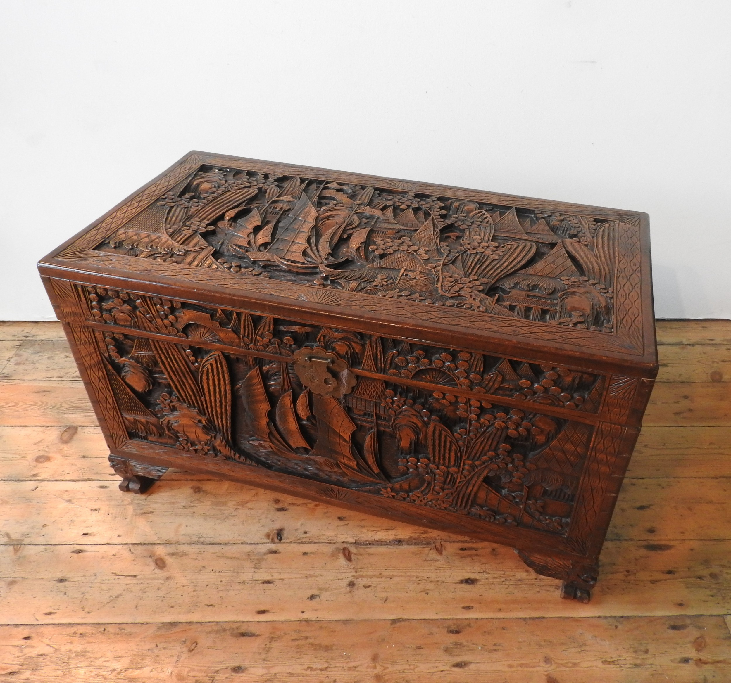 AN ORNATE CARVED CAMPHORWOOD BLANKET CHEST , with two carved handles and claw feet,  62 x 98 x 54 cm