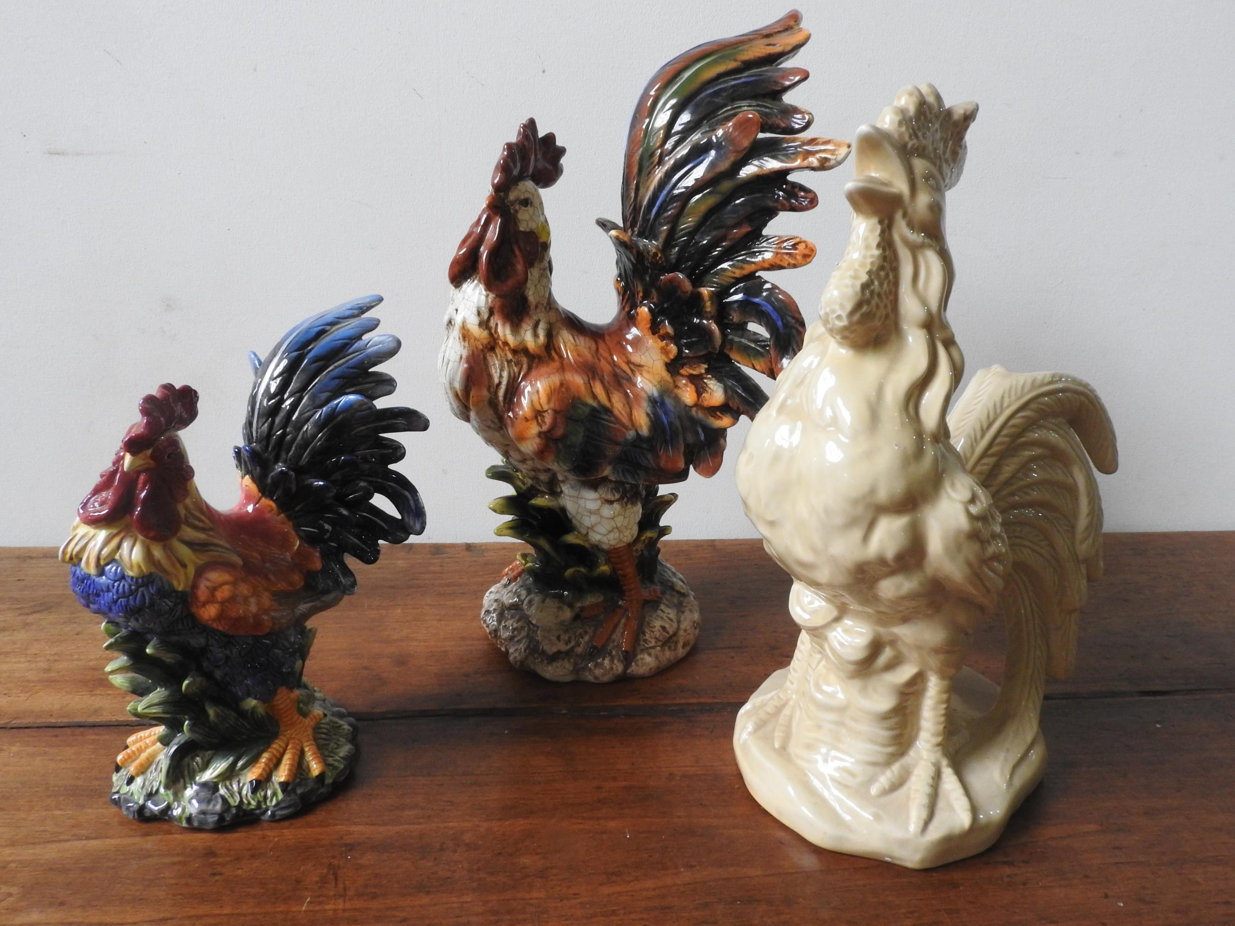 THREE 20TH CENTURY GLAZED COCKEREL ORNAMENTS, two painted and one cream glazed, the largest 48 cm