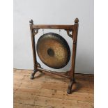 A COPPER GONG SUSPENDED ON A GOTHIC STYLE OAK STAND, the stand with quatrefoil decoration, the