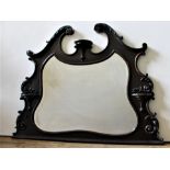 AN ORNATE CARVED FRAMED OVERMANTEL MIRROR, the bevelled mirror contained within an ornate scroll