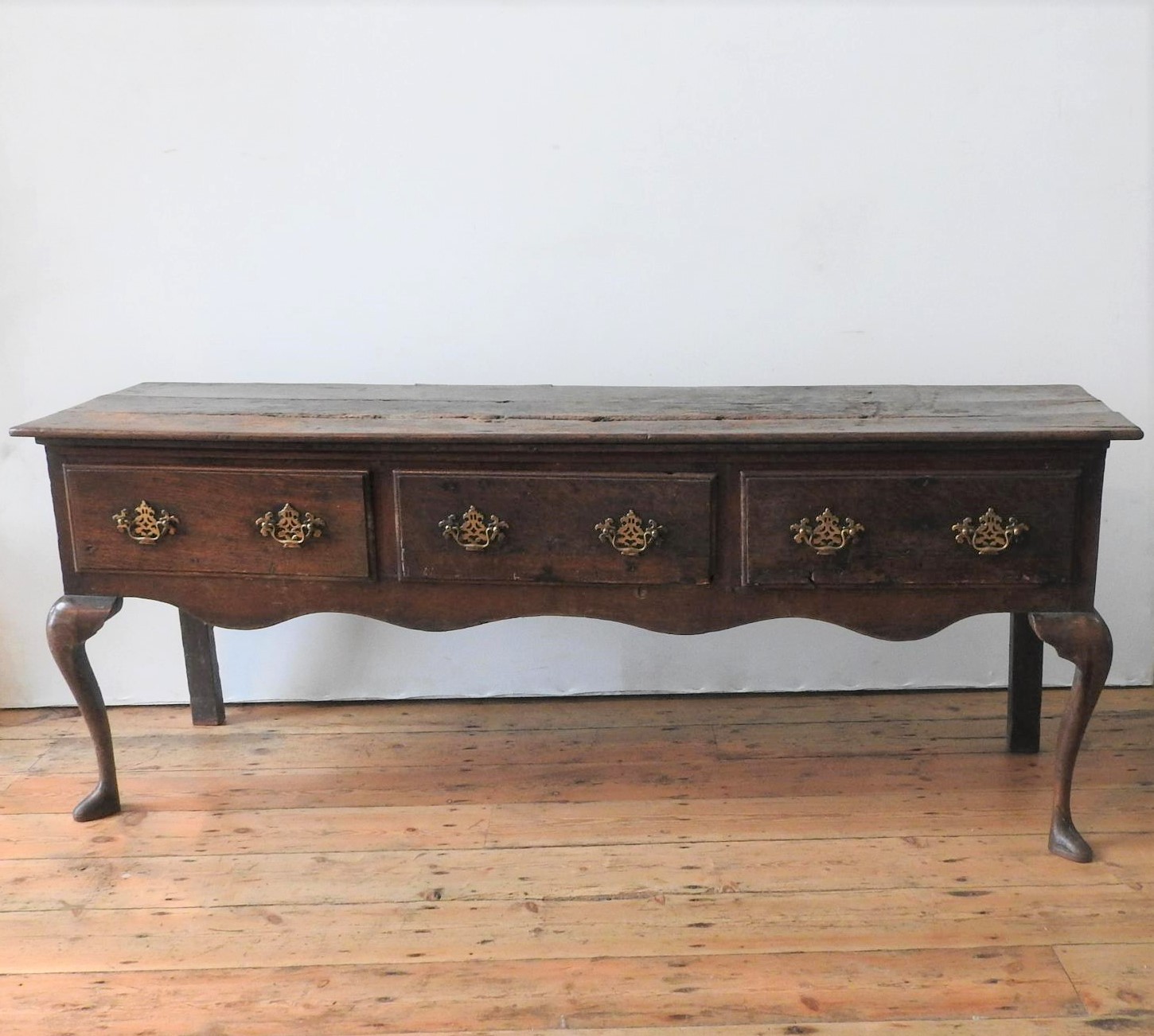 AN EARLY 19th CENTURY OAK THREE DRAWER DRESSER BASE, on Queen Anne front legs, the drawers with