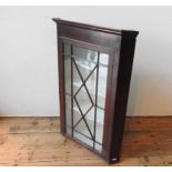 A GEORGE III GLAZED MAHOGANY WALL MOUNTED CORNER CUPBOARD, with three serpentine shape shelves and