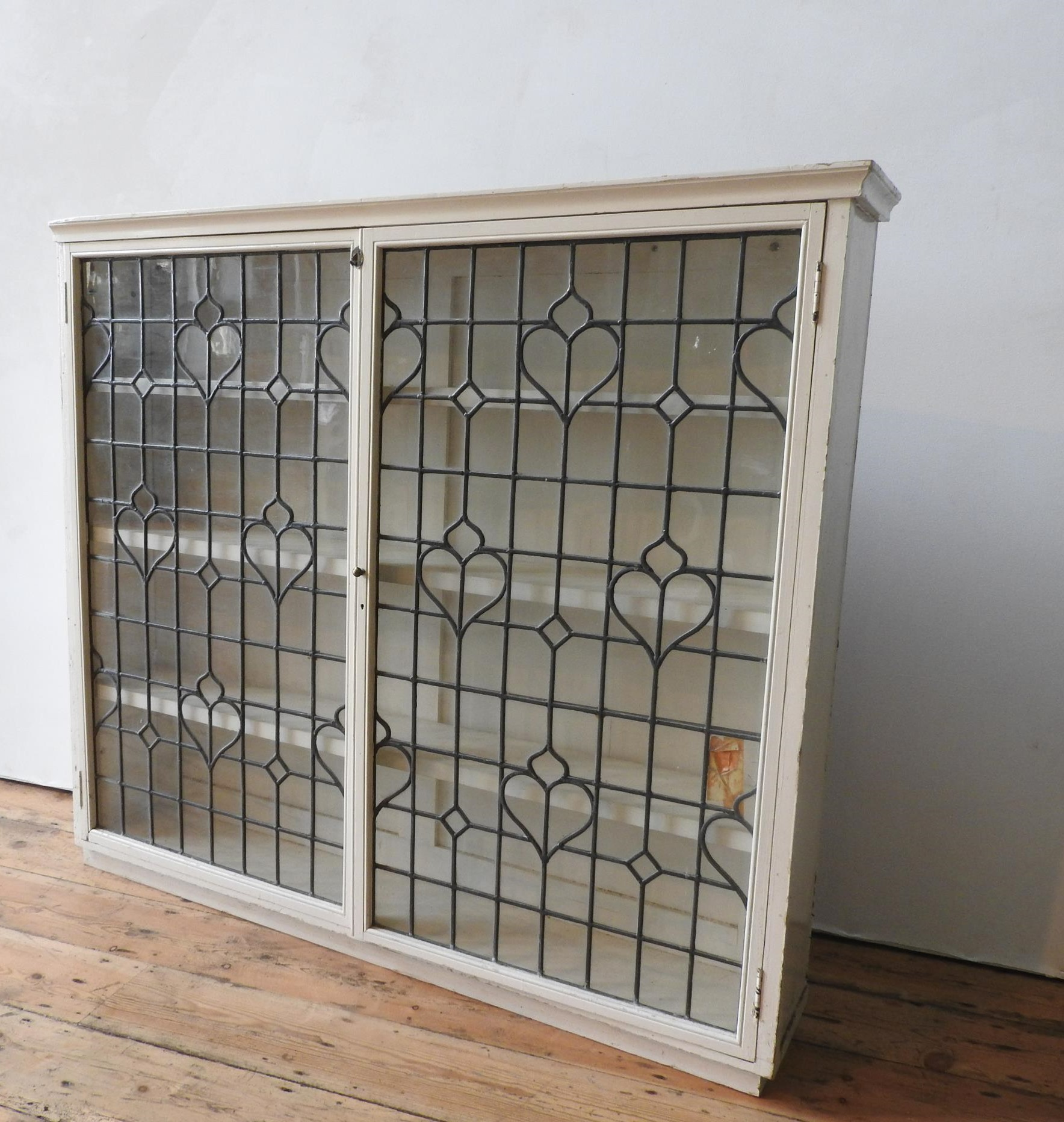 A CREAM PAINTED LEADED LIGHT TWO DOOR BOOKCASE, with three interior shelves, 113 x 126 x 24cm