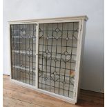 A CREAM PAINTED LEADED LIGHT TWO DOOR BOOKCASE, with three interior shelves, 113 x 126 x 24cm