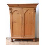 A 19TH CENTURY WAXED PINE ARCH PANELLED CUPBOARD, with cornice, bookcase stands on an oak base,