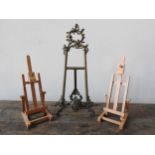 AN ORNATE METAL TABLE TOP EASEL / PICTURE STAND AND TWO WOODEN DESK EASELS