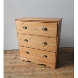 A WAXED PINE CHEST OF THREE DRAWERS, the three drawers with brass cup handles set in a useful