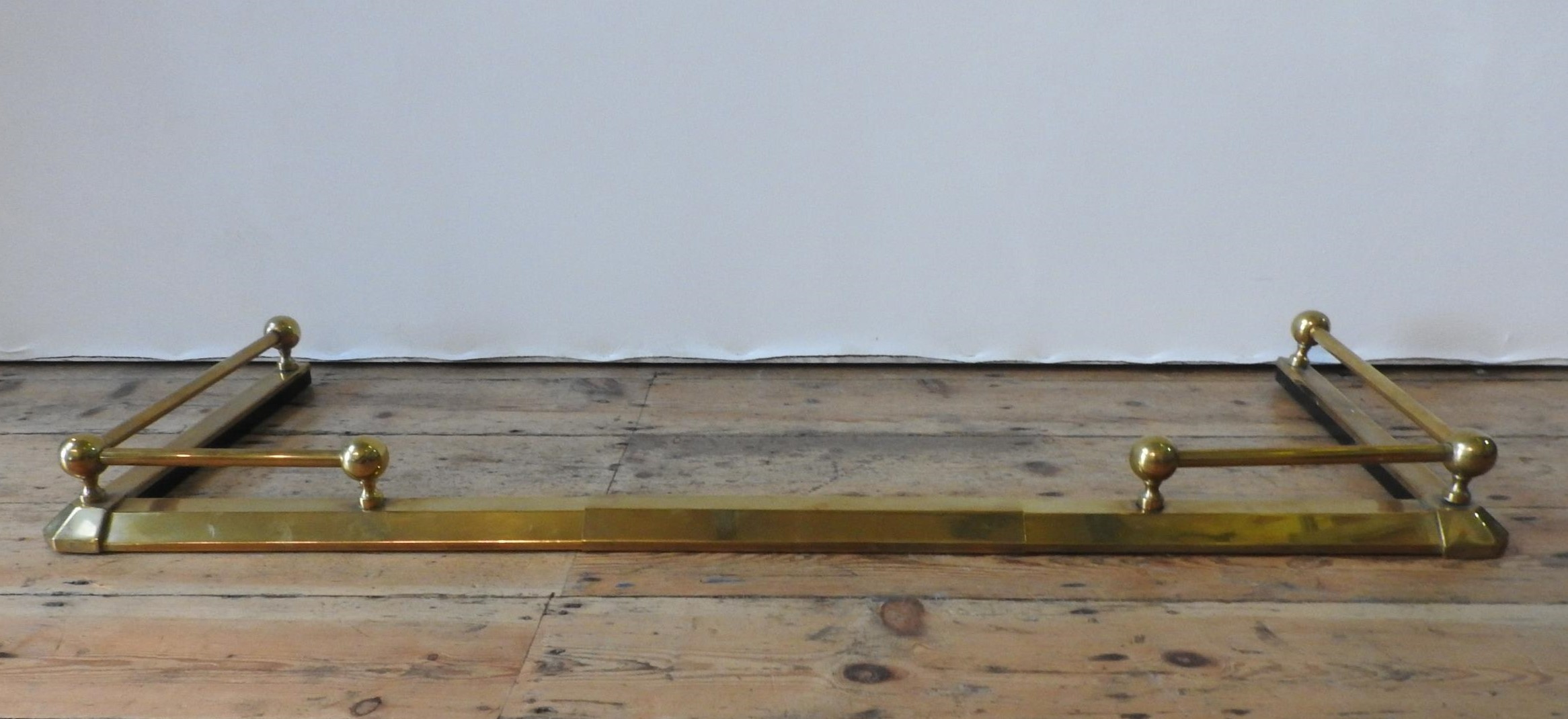 A 20TH CENTURY BRASS ADJUSTABLE FIRE CURB, with rail and finials, 120 cm at it's smallest