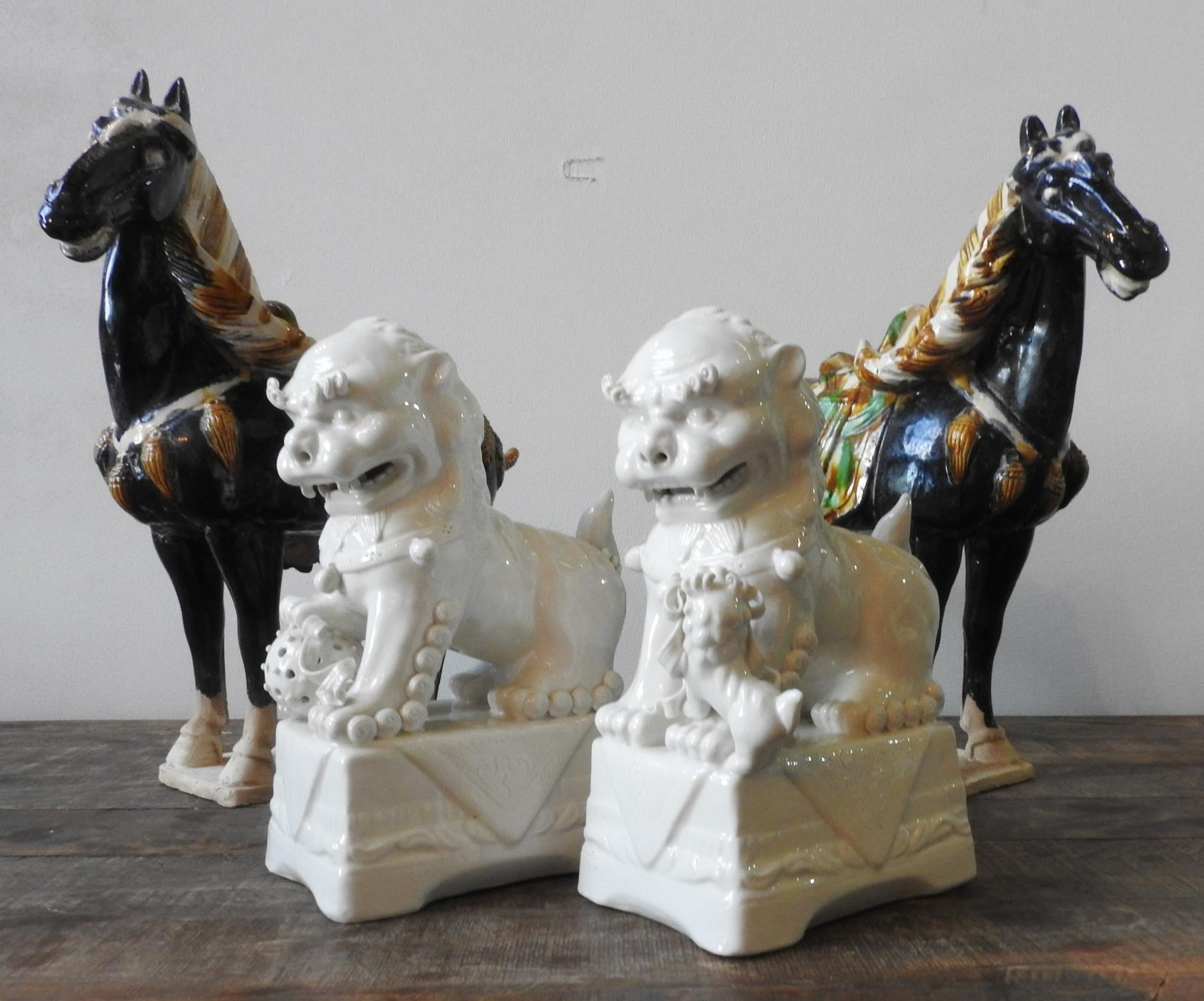 A PAIR OF BLANC DE CHINE LION FIGURES AND TWO TANG-STYLE HORSE FIGURES