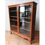 A MAHOGANY CROSS BANDED TWO DOOR GLAZED BOOKCASE ON SPLAYED BRACKET FEET, 145 x 126 x 37.5 cm