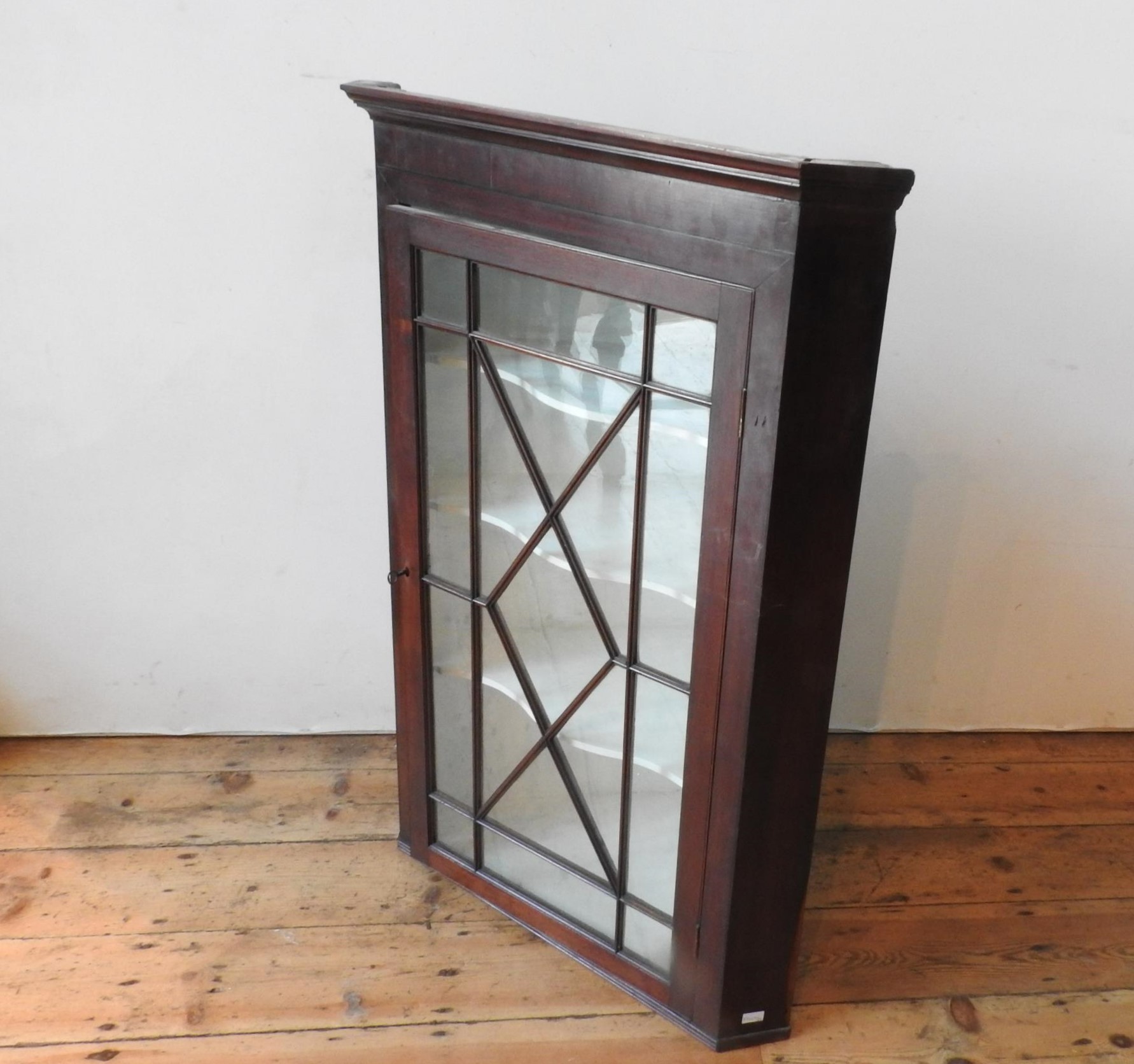 A GEORGE III GLAZED MAHOGANY WALL MOUNTED CORNER CUPBOARD, with three serpentine shape shelves and