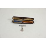 Silver napkin clip, maker GEW, Birmingham 1907, & a white metal banded, enamel & amber cheroot with