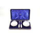 Cased silver set of a pair of scallop-shaped butter dishes & knives, maker HW & Co LD, London 1908-9